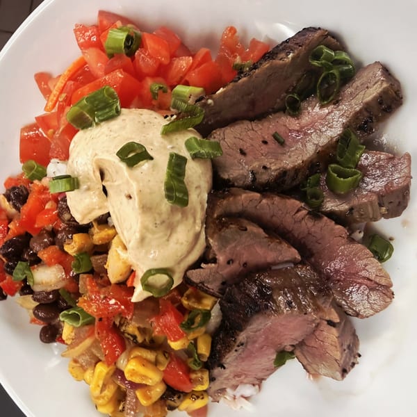 Sliced steak, black bean and corn salsa, diced tomatoes, and a creamy sauce, garnished with scallions.